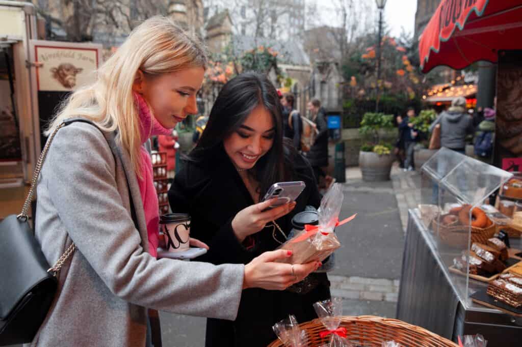 Young ladies taking a photo of sweets sold in the market